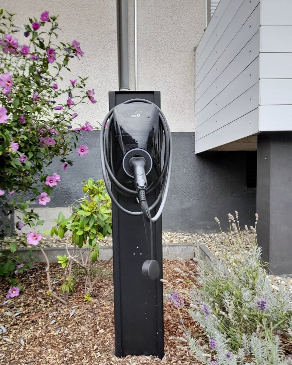 FOX Wallbox auf Standsäule im Garten mit aufgerolltem Ladekabel